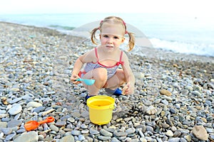 Cute happy little girl plays on the beach
