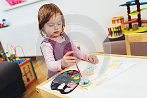 Cute happy little girl, preschooler, painting with water color