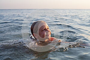 Cute happy little girl swiming at the ocean