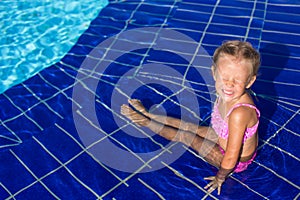Cute happy little girl in the swimming pool looks