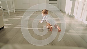 Cute happy little toddler baby boy is crawling on a wooden floor at home. Concept: life, childhood, first year of life
