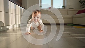 Cute happy little toddler baby boy is crawling on a wooden floor at home. Concept: life, childhood, first year of life