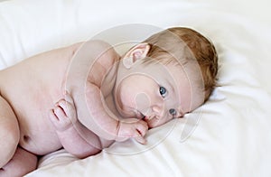 Cute happy 3 month baby boy or girl lying on a white sheet