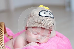 Cute happy newborn baby in dragon knitted cap sleeping on pink blanket. Infant sleeping portrait.