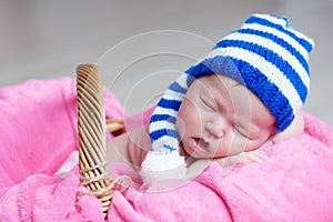 Cute happy newborn baby in striped knitted cap sleeping on pink blanket. Infant sleeping portrait