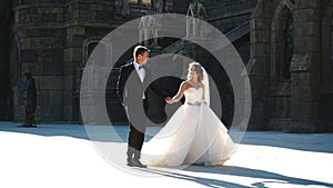 Cute happy newlywed couple having fun near old castle wall