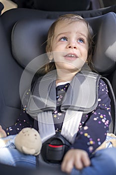 Cute happy small girl in car seat in the car