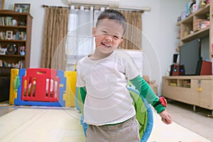 Cute happy smiling Asian little boy playing and having fun inside toy tunnel tube indoor at home