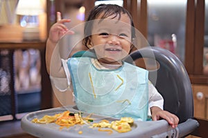 Cute happy smiling Asian toddler baby girl eating by hands, Little kid eating food with BLW method, baby led weaning, Infant