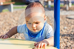 Cute happy smiling baby boy walking at children playground outdoors