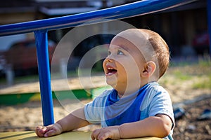 Cute happy smiling baby boy walking at children playground outdoors