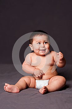 Cute happy smiling baby sitting wearing diaper