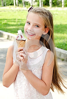 Cute happy smiling little girl child eating an ice cream outdoor