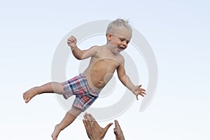 Cute happy smiling toddler having fun on the sea. Father throwes up his little son