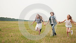 Cute happy teens holding hands and running on field