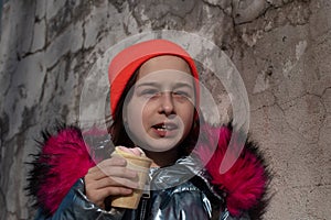 Cute Happy Toddler Girl in Winter Hat Eating Ice-Cream.Girl eating ice cream in winter.Portrait of a girl of 9 years old