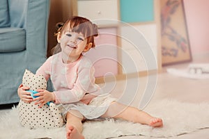 Cute happy 2 years old baby girl playing with toys at home