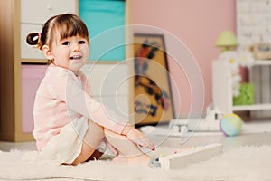 Cute happy 2 years old baby girl playing with toys at home