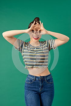 Cute happy young Asian woman making funny face over green background