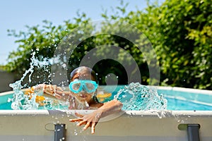 A cute happy young girl child playing in swimming pool wearing blue diving mask