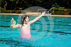 Cute happy young girl in goggles swimming and snorking in the swimming pool. Happy child in summer in outdoor pool