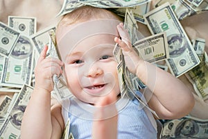 Cute hapy baby boy playing with a lot of money, american hundred dollars cash