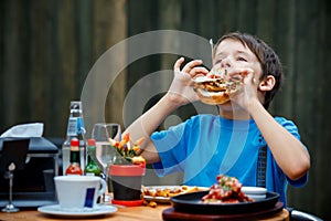 Cute healthy teenager boy eats hamburger and potato