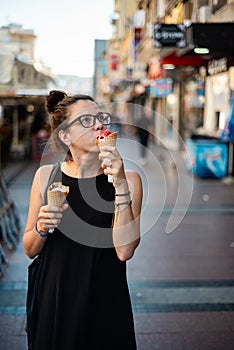 Girl eating two ice creams on the street