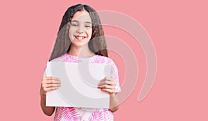 Cute hispanic child girl holding blank empty banner looking positive and happy standing and smiling with a confident smile showing
