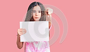 Cute hispanic child girl holding blank empty banner pointing with finger to the camera and to you, confident gesture looking