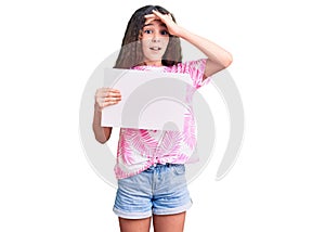 Cute hispanic child girl holding blank empty banner stressed and frustrated with hand on head, surprised and angry face