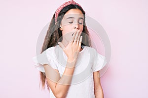 Cute hispanic child girl wearing casual clothes and diadem bored yawning tired covering mouth with hand