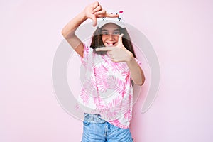 Cute hispanic child girl wearing casual clothes and funny kitty cap smiling making frame with hands and fingers with happy face