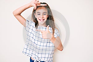 Cute hispanic child girl wearing casual clothes smiling making frame with hands and fingers with happy face