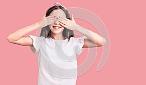 Cute hispanic child girl wearing casual white tshirt covering eyes with hands smiling cheerful and funny