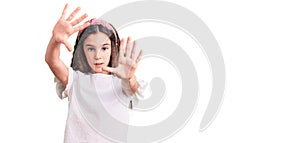 Cute hispanic child girl wearing casual white tshirt doing frame using hands palms and fingers, camera perspective