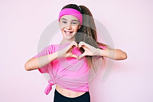 Cute hispanic child girl wearing sportswear smiling in love showing heart symbol and shape with hands