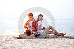 Cute hispanic couple playing guitar serenading on beach photo