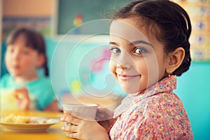 Cute hispanic girl drinking milk at school photo