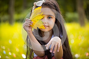 Cute hispanic girl hiding over yellow leaf