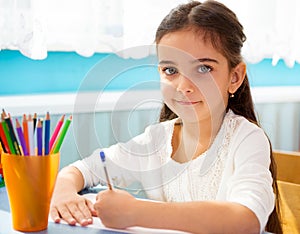 Cute hispanic girl writing at school