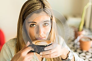 Cute Hispanic woman drinking coffee