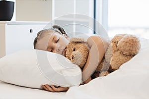 Cute ill girl sleeping sweet with teddy bear at home