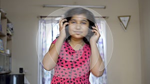 Cute Indian asian caucasian girl enjoying listening music on mobile with headphone nodding and dancing portrait front view.