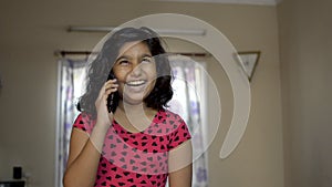 Cute Indian Asian caucasian happy girl child having fun time talking to friend on mobile phone call front view portrait