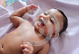 A cute indian innocent new born baby in a jovial mood with a charming smile