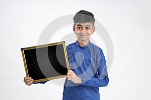 Cute indian little boy showing black board with copy space over white background
