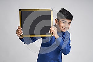 Cute indian little boy showing black board with copy space over white background