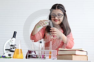 Cute Indian school girl in India traditional dress costume doing science experiments in laboratory, young scientist kid with photo