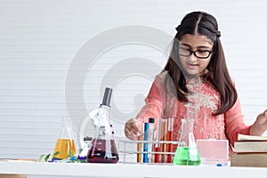 Cute Indian school girl in India traditional dress costume doing science experiments in laboratory, young scientist kid with photo